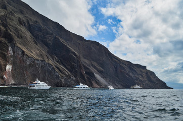 Fototapeta na wymiar Line of Boats Near Cliff in the Galapagos Islands Ecuador