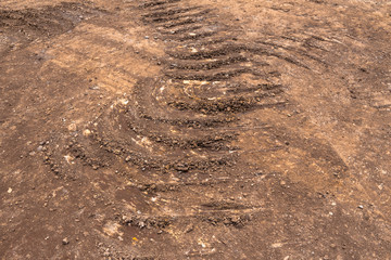 Cascading circle-shaped scratches left by construction vehicles as they pass through dirt roads