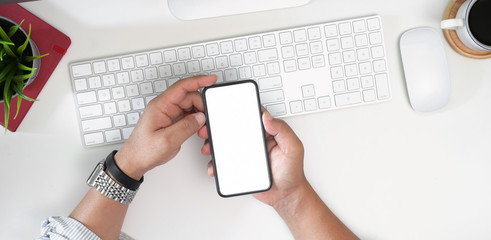 Man using mobile phone and laptop on workspace table
