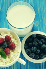 Cottage cheese with berries, waffles and milk on a wooden blue background. Top view.