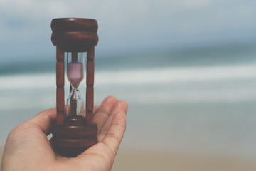 Small hourglass show time is flowing on old wood grunge texture.