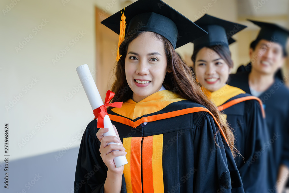 Wall mural Female university graduates celebrate happily after completed and received diploma degree certificate in commencement ceremony. The women graduate express congratulations with each other.