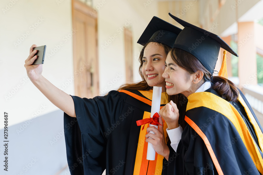 Wall mural female university graduates celebrate happily after completed and received diploma degree certificat