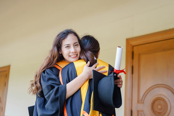 Female university graduates celebrate happily after completed and received diploma degree certificate in commencement ceremony. The women graduate express congratulations with each other.