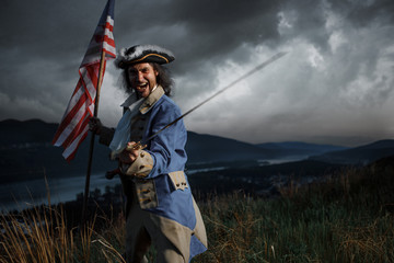 Man in United States War of Independence soldier costume with flag posing in forest. 4 july...