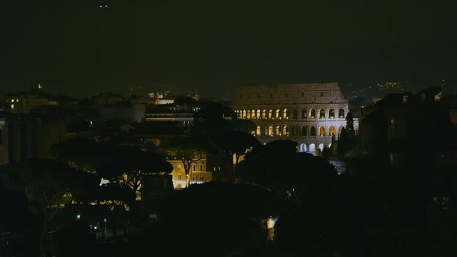 Coliseum "Colosseo, Anfiteatro Flavio" zoom in from Vittoriano Monument at night with low lights. City lights and airplane passing by. Shot on Red Monstro 8K. In 4K
