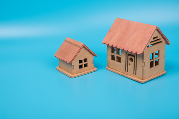 Two houses on a blue background background, copy space. Natural wood, Eco-friendly housing.