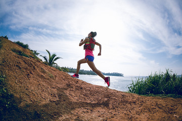 Woman trail runner running on seaside hills