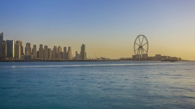 The Ain Dubai ferris wheel under construction, sunset over Bluewater Island, panoramic view of cityscape, time lapse, Dubai, UAE.