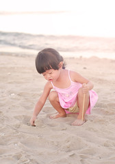 Fototapeta na wymiar Portrait Kid girl playing sand at the beach