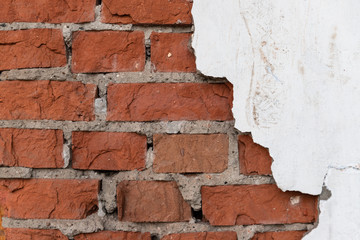 Old red brick wall with collapsed white plaster.
