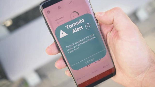 Receiving a TORNADO warning notification on a smartphone screen. Blinking alert concept