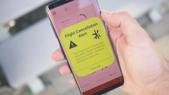 Receiving a FLIGHT CANCELLATION warning notification on a smartphone screen. Blinking alert concept