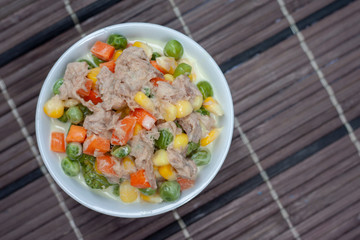 Top view salad vegetables with tuna in white bowl.