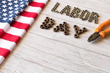 Labor day. American flag and Inscription labor day and various tools on a light wooden background.