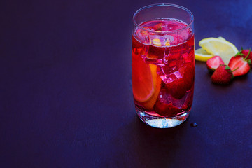 Drink with ice from strawberries on a dark background. Fresh strawberry cocktail. Fresh summer cocktail with strawberry and ice cubes. Glass of strawberry soda drink on dark background.