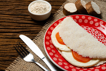 Casabe (bammy, beiju, bob, biju). Flatbread of cassava (tapioca) with caprese salad (tomato, mozzarella) on plate old wooden background. Selective focus.