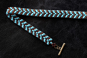 Peyote choker necklace made of seed beads on a dark background close up