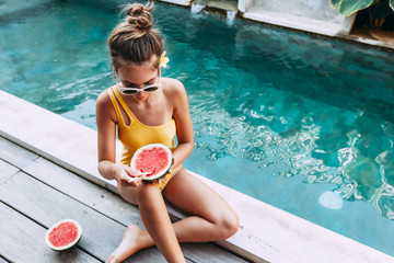 Girl eating watermelon in pool on luxury villa in Bali