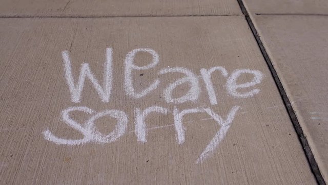 We are sorry message written in sidewalk chalk