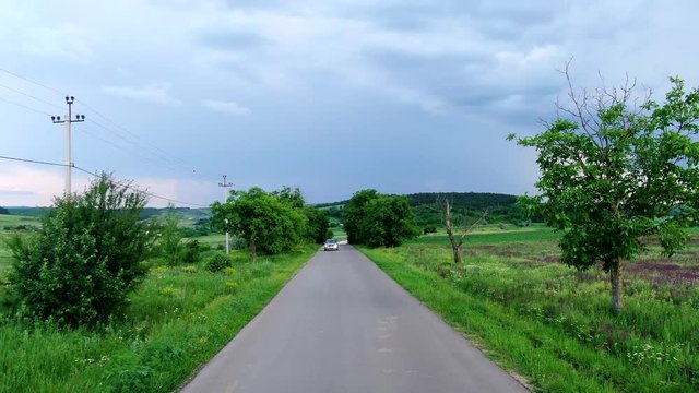 A passing car on a narrow road near an abandoned village.