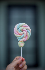 One of colorful Marshmallow hold by hand dark background.