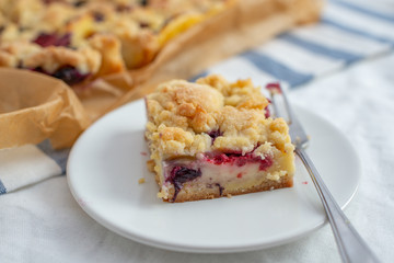 Sweet delicious crumble cake in a baking form and pieces of the cake on a table