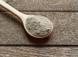 white pepper in wood spoon on wood background.