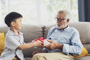 Obraz premium senior man happiness and grandson are sitting on the sofa and give .gift at living room together