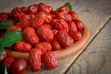 China xinjiang red date with green leaves on wooden plate for soup making purposes.