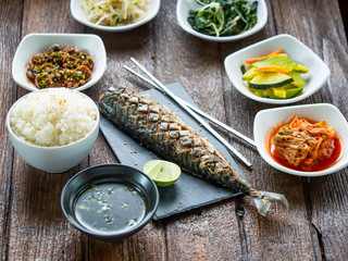 One set of saba grill serve with slide dish, kimchi, rice and seaweed soup with korean style serve menu on wood table.