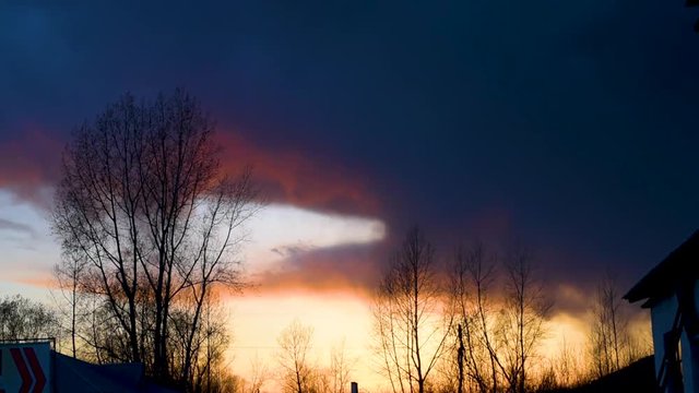 Bright sunset or sunrise on a dark sky with thunderclouds. Sunset or sunrise with dark clouds and sunlight , against the light 