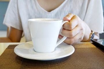 Selective focus of woman holding coffee cup on blurred background in the café, space for your text, in the morning