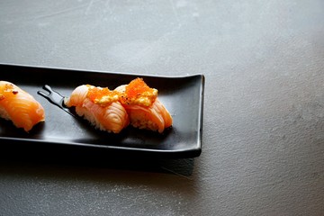Japanese food style, Selective focus of salmon cream cheese sushi with teriyaki sauce on black plate on stone cutting board in restaurant, Ready to eat or serve (salmon aburi sushi),on dark background
