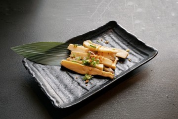 Selective focus of Stir fried mushrooms with butter sprinkled with scallion sliced in black plate on stone cutting board in restaurant, ready to eat or serve (Pleurotus Eryngii,King Oyster Mushroom)