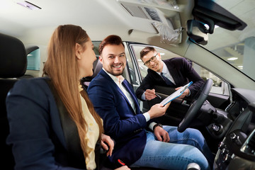 A young couple buys a car in the auto salon