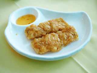 A plate of tasty deep fried bean curd or tofu stuffed with shrimp served with dipping sour and sweet plum sauce, selective focus.
