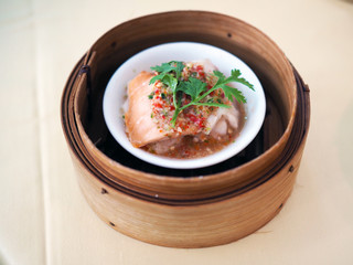 A bamboo basket of steamed salmon with spicy and sour sauce. kind of yum cha or dimsum Chinese traditional food style with selective focus.
