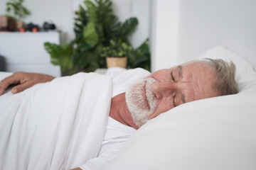 senior man sleeping alone and headache or dreaming nightmare on bed in room