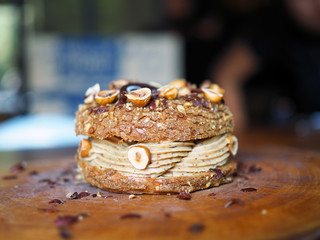 Paris Brest, a classic French dessert consist of large baked ring of choux pastry, filled with soft hazelnut cream topped with roasted hazelnut. Selective focus.