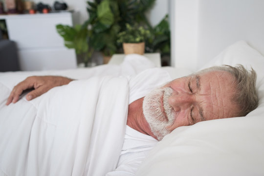 senior man sleeping alone and headache or dreaming nightmare on bed in room