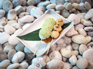 Mitarashi Dungo, round shape made of dough then grilled or burned topped with chopped edamame . Traditional Japanese dessert with selective focus.