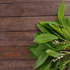The decor of the flowers of lily of the valley on the background of vintage wooden boards. Vintage background with frame of flowers and place under the text. Flat lay.