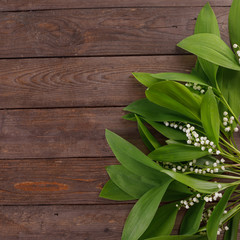 The decor of the flowers of lily of the valley on the background of vintage wooden boards. Vintage background with frame of flowers and place under the text. Flat lay.