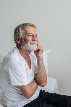 senior man thinking or try to remember alone on bed in white room