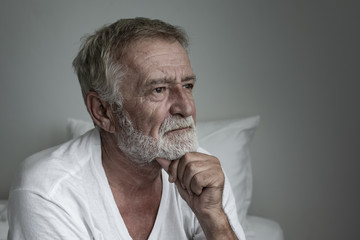 senior man thinking or try to remember alone on bed in white room