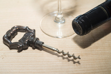 vintage wine opener, glass and wine bottle on a wooden background