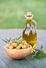 Fresh healthy green olives with rosemary and virgin oil in a bottle on wooden table