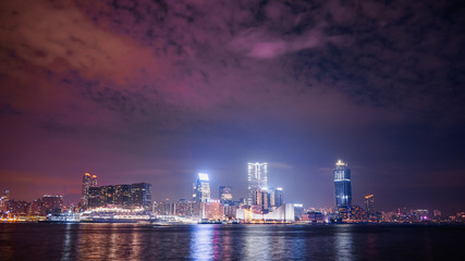 Fototapeta na wymiar Hong Kong city’s skyline with Victoria Habour at night, shot from HK island side, with a colourful sky showing the lights pollution from skyscrapers.