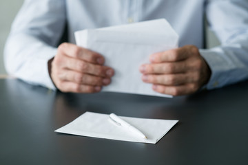 Business correspondence. Cropped shot of man sitting at desk with stack of white envelopes and blank sheet of paper. Copy space.